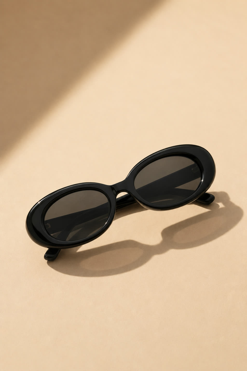 The same sunglasses produced as a flat lay on a sandy tan surface