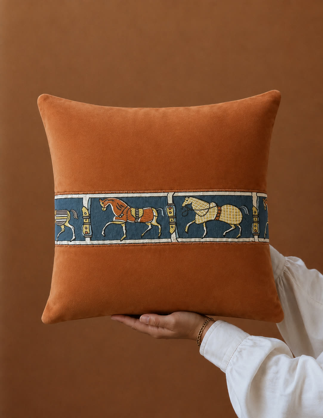 Finished product image of the same cushion, the woven horse band reproduced exactly against a warm ground