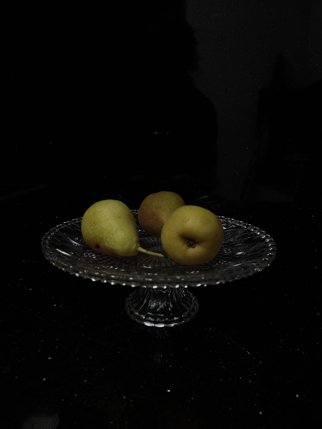 Phone photograph of pears on a dark plate, taken in low light