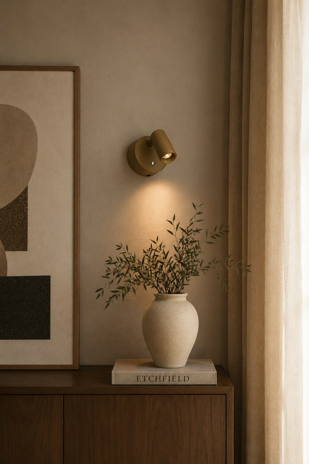The sconce lighting a console table styled with framed art and a vase of branches